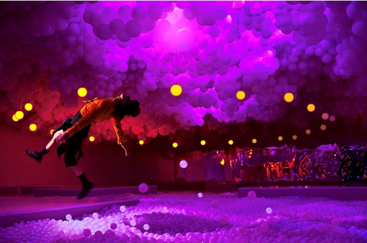 Una performance in un ambiente immersivo con sfere rosa e viola